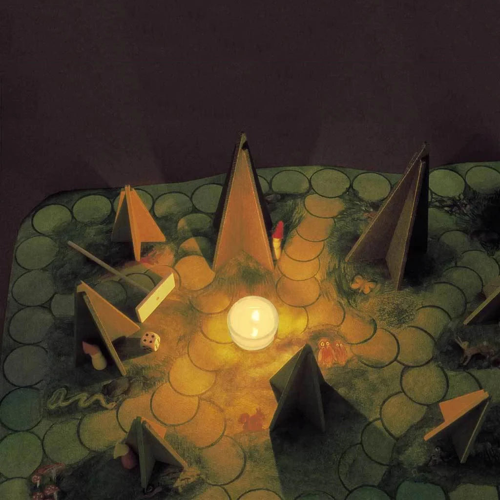 Tealight illuminates a board game with a shadowy forest theme