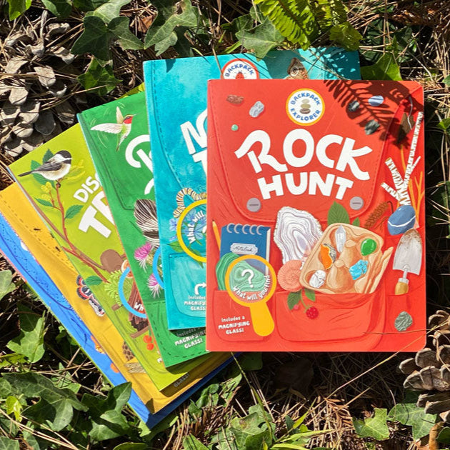 Set of children's activity books on a natural background with leaves and pine cones.