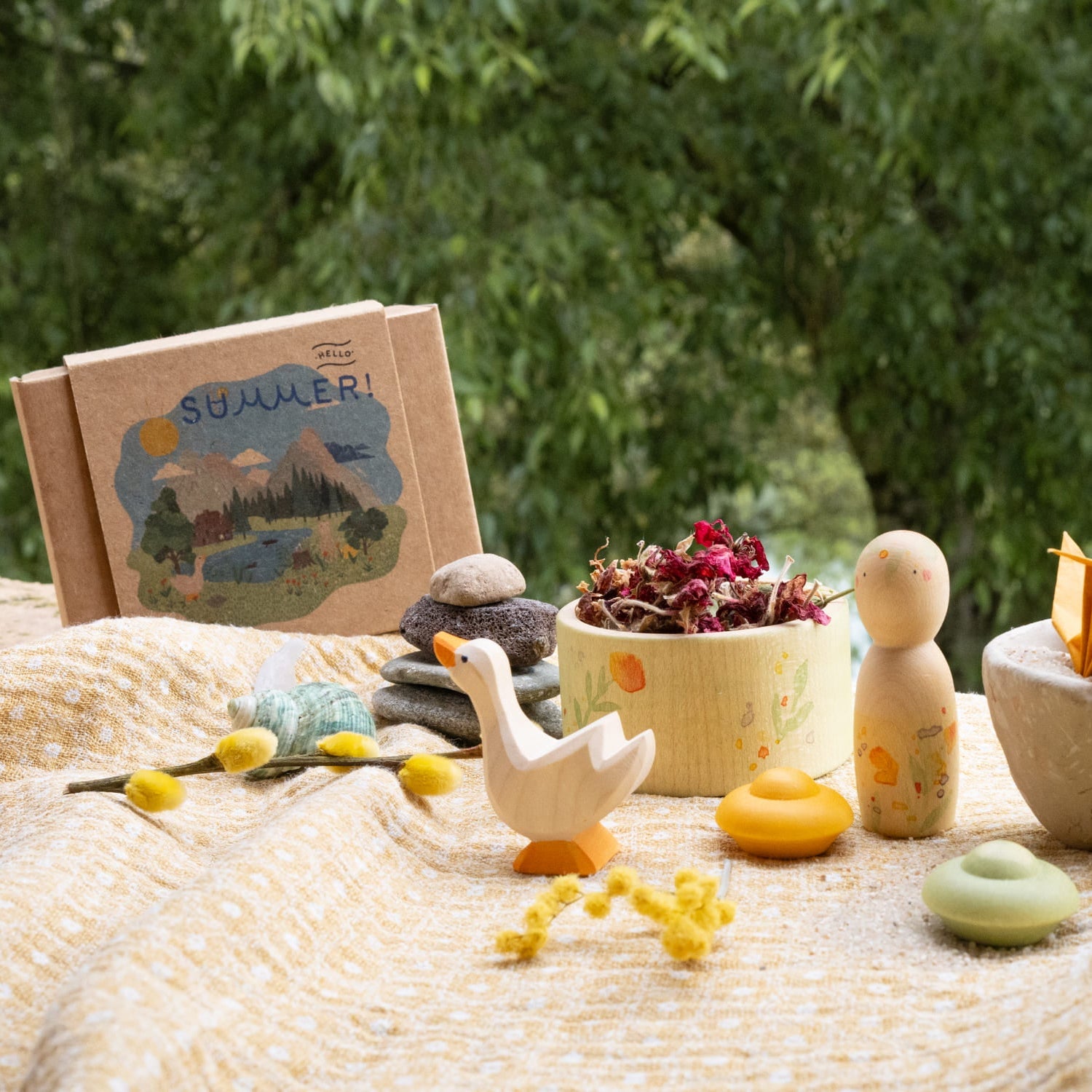 Children's toys and a book titled 'Summer' on a textured surface with greenery in the background