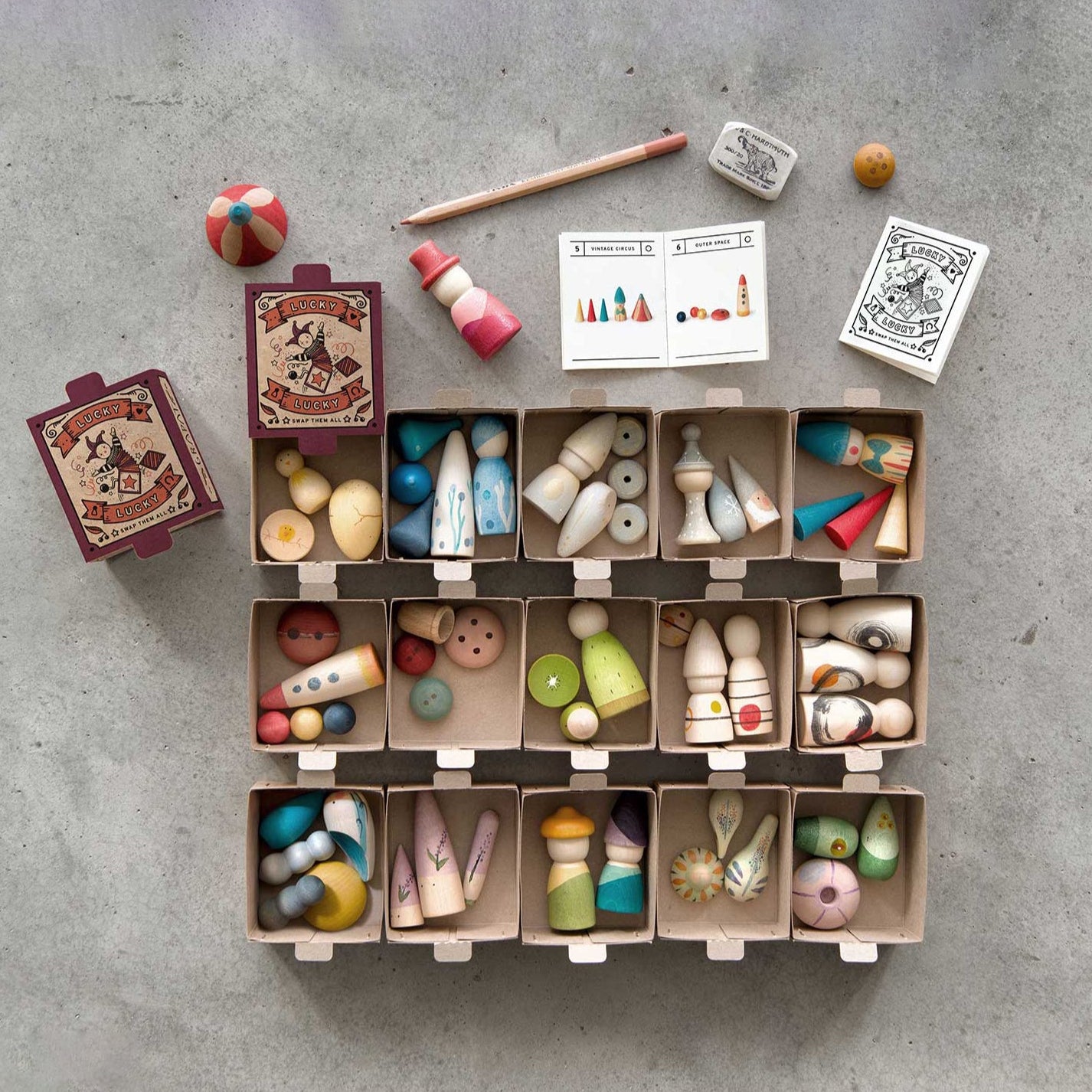 Collection of small Grapat brand wooden toys and accessories on a gray surface.