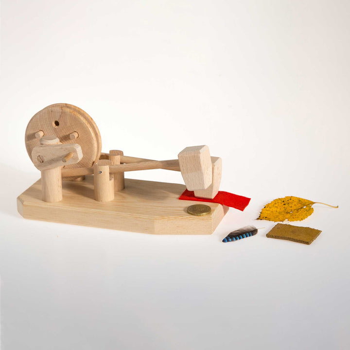 Wooden Toy Science Experiment Hammer Mill Physics kit on white background with leaf, feather, and coin for size reference
