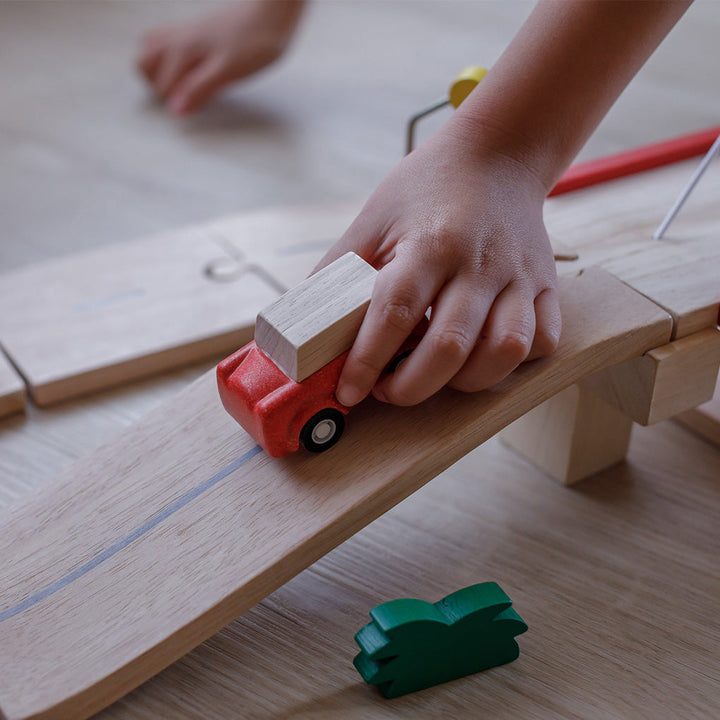 Child playing with Plan Toys wooden car track
