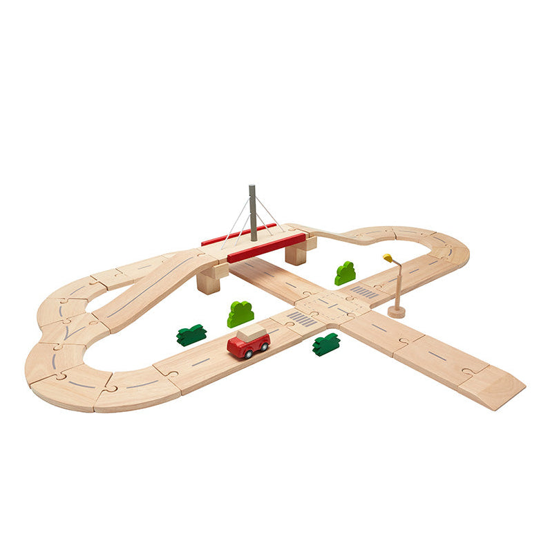 Plan Toys wooden toy roads set with a red vehicle and green trees on a white background