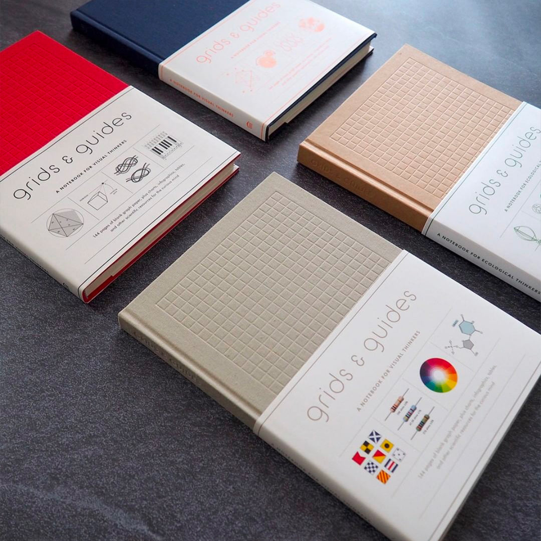 Set of four Grides and Guides notebooks on a dark slate surface.