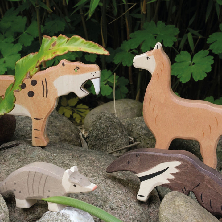 Holztiger wooden animal figurines on rocks with a natural background