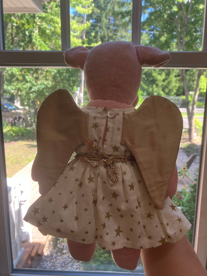 Senger plush Angel pig with wings with star pattern dress held in front of a window