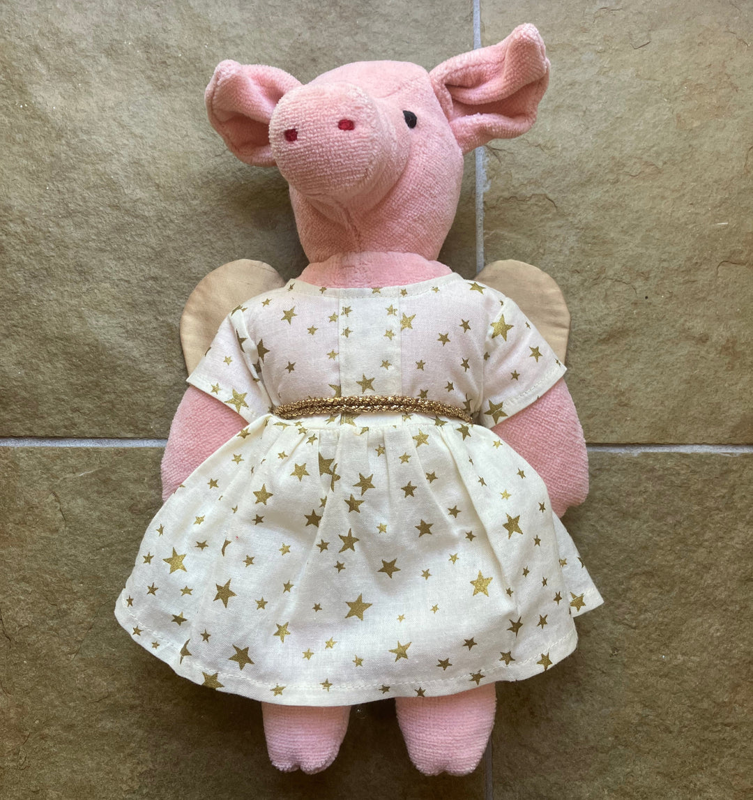 Pink stuffed animal wearing a white dress with gold stars on a tiled floor.