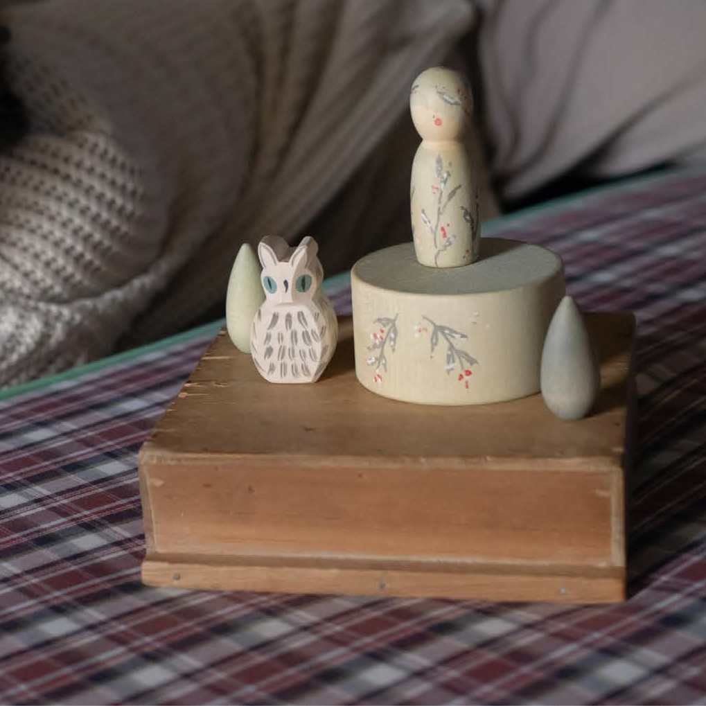 Child next to Ostheimer white owl and Grapat bowl and winter peg doll and mandalas wooden figurines.