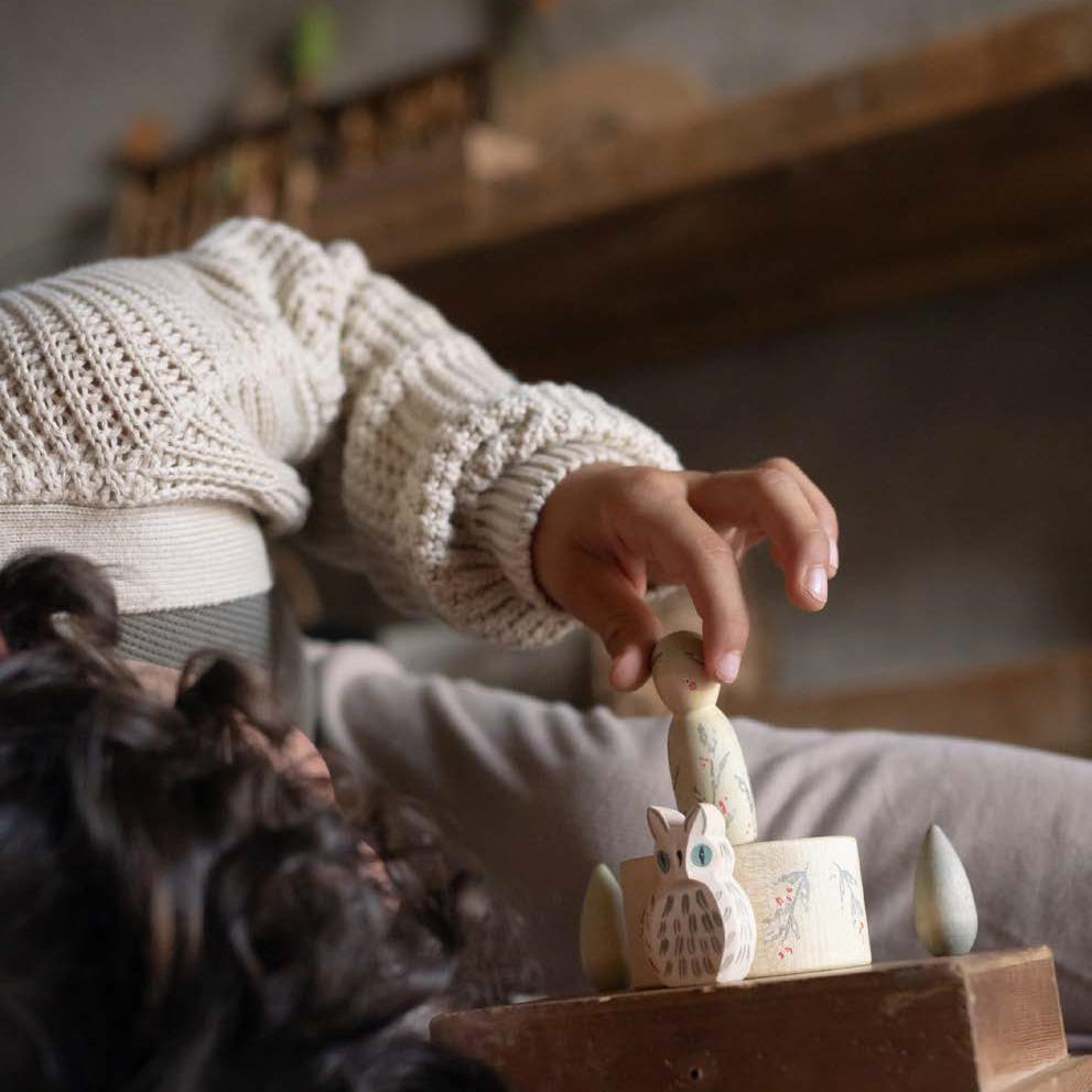 Child playing with Ostheimer owl and Grapat peg doll wooden toys.
